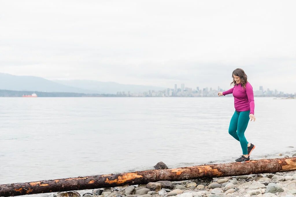 Marisa Mae mid-stride along the False Creek seawall, Vancouver skyline in the background
